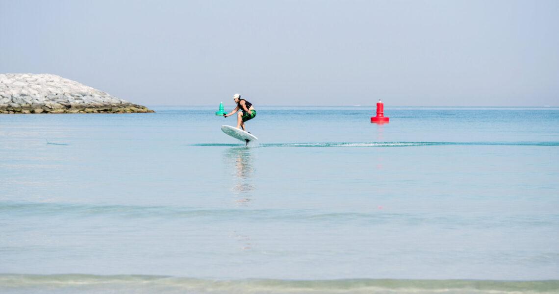 Mann gleitet auf einem E Surfboard über das wellenlose Meer