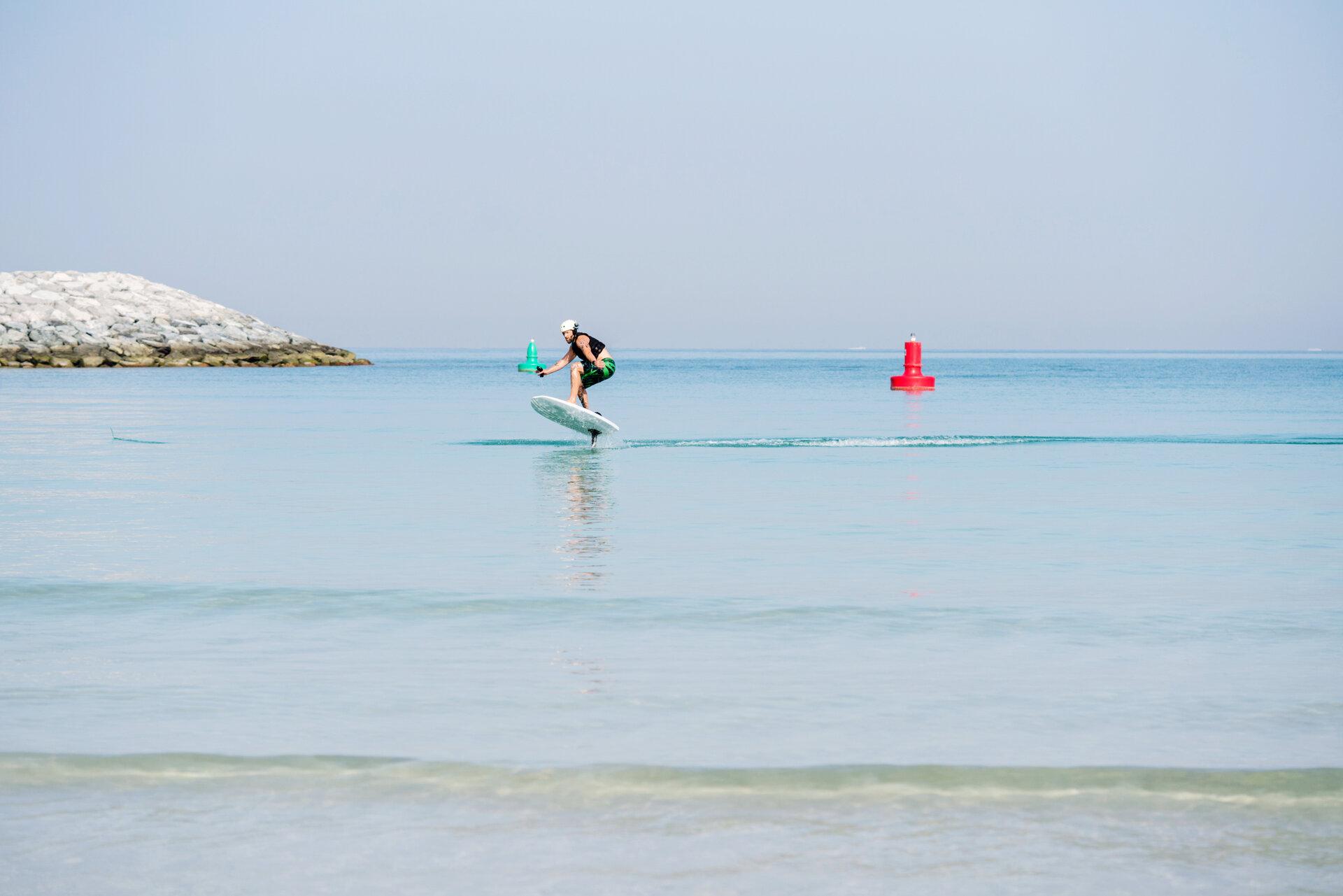 Mann gleitet auf einem E Surfboard über das wellenlose Meer
