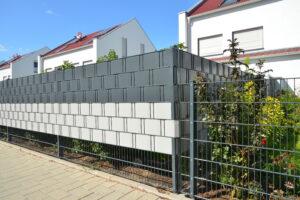 Verzinkter Stahlgitterzaun mit Kunststoff-Sichtschutzfolie als Einfriedung um den Garten eines Einfamilienhauses.