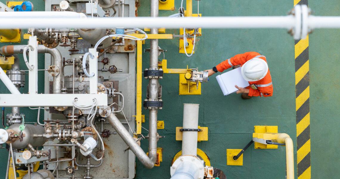 Arbeiter, der den Zustand einer Kreiselpumpe überprüft, um die Zuverlässigkeit des Öl- und Gasproduktionsprozesses aufrechtzuerhalten, auch im Rahmen des Arbeits- und Gesundheitsschutzes.