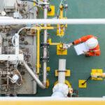 Arbeiter, der den Zustand einer Kreiselpumpe überprüft, um die Zuverlässigkeit des Öl- und Gasproduktionsprozesses aufrechtzuerhalten, auch im Rahmen des Arbeits- und Gesundheitsschutzes.